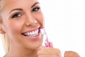 young blonde woman with very white teeth and pink toothbrush